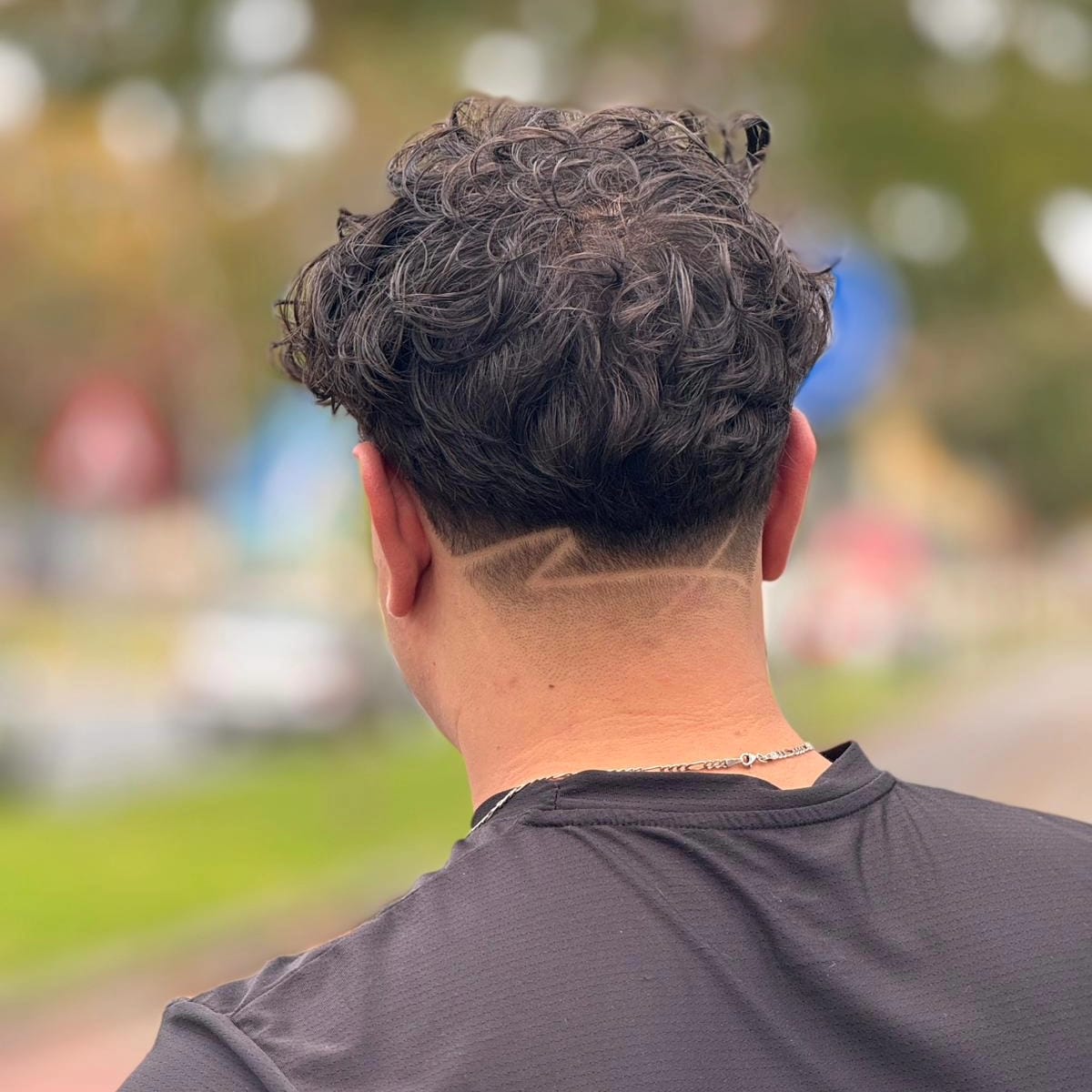 Krullend herenkapsel met opgeschoren nek, van achteren gezien